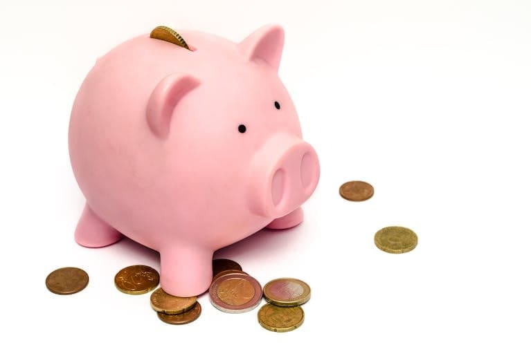 A pink piggy bank surrounded by scattered coins, symbolizing emergency savings.
