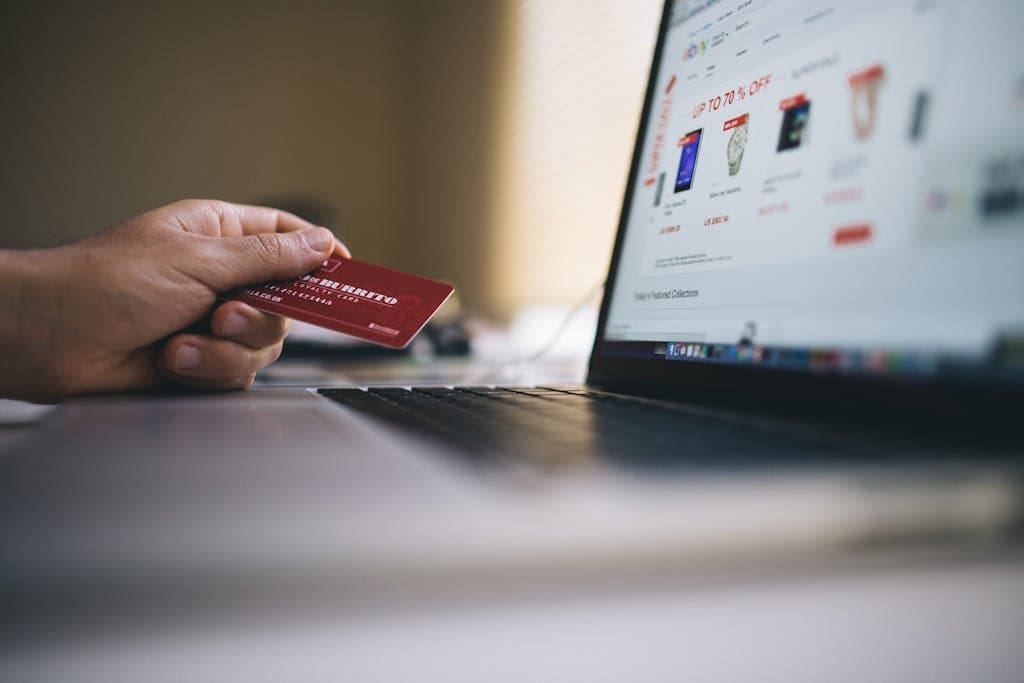 Business owner holding a credit card while shopping online on a laptop.